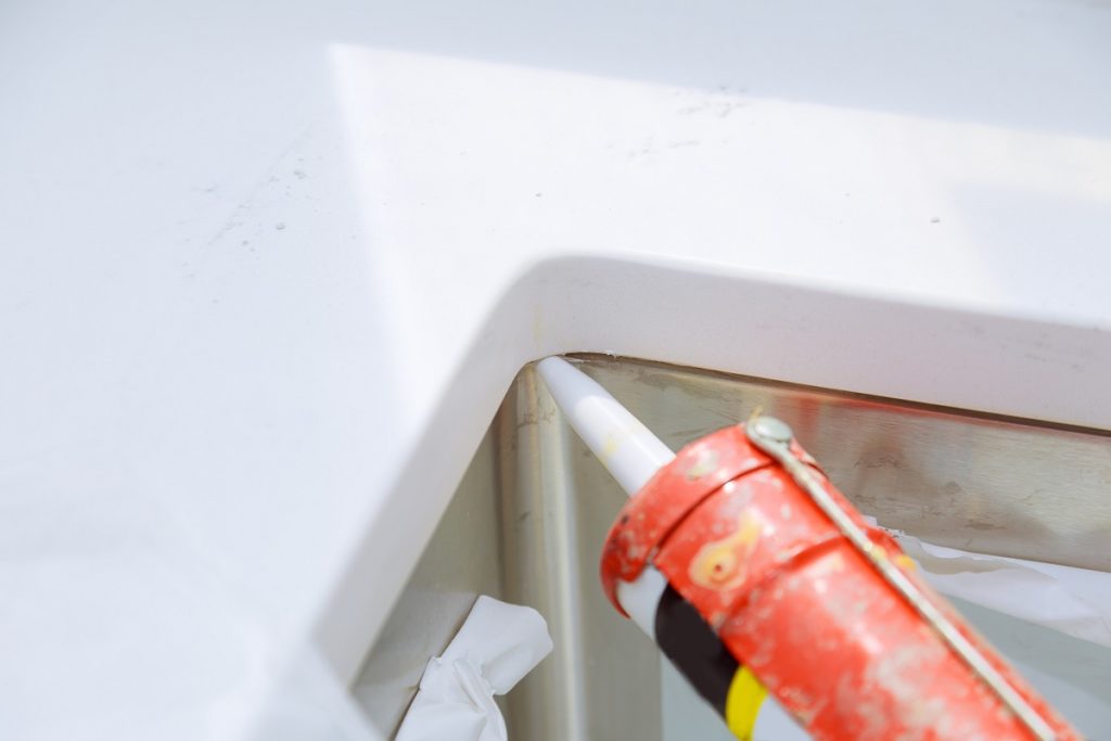 Worker installing granite sink in kitchen silicone sealant on granite countertops